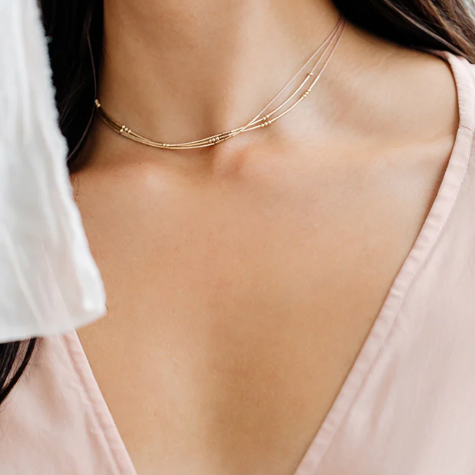 The Pictor is a triple-stranded silk cord necklace stacked with gold tubes and rounds that shift freely. By Abacus Row, this necklace is made with a lighter weight cord which gives it an elegant drape.