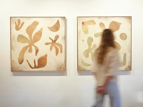 Two abstract artworks by Danielle Hutchens, on a living room wall with a blurred person in the foreground.