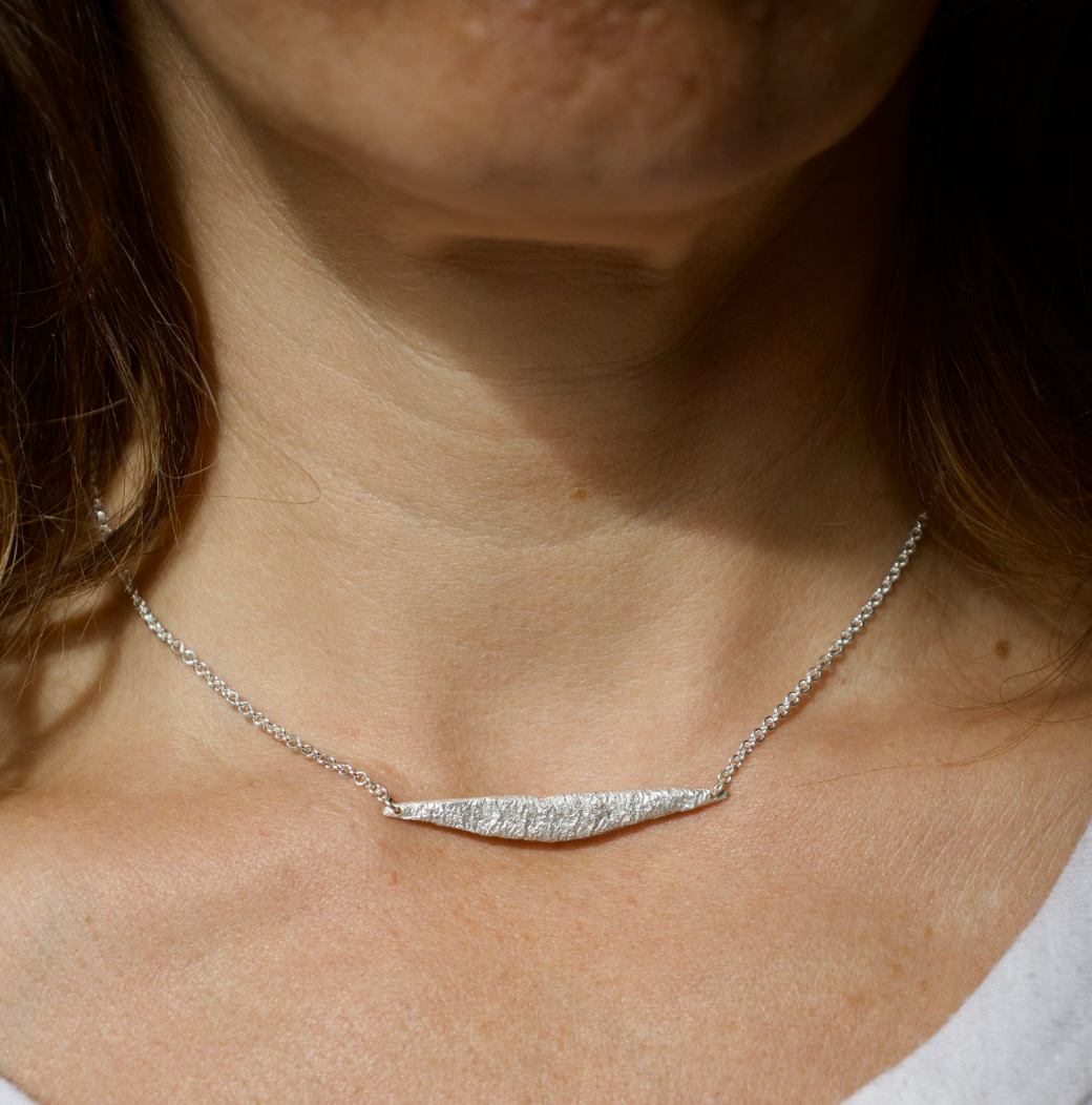 Hand fabricated sterling silver necklace with a curved bar. A simple design of a two inch wide torch textured piece of sterling silver strung on bright silver 2mm cable chain. Great for layering or a stand alone everyday piece.