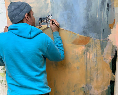 Artist Michael McConnell painting an abstract landscape with a realistic animal painting of a coyote