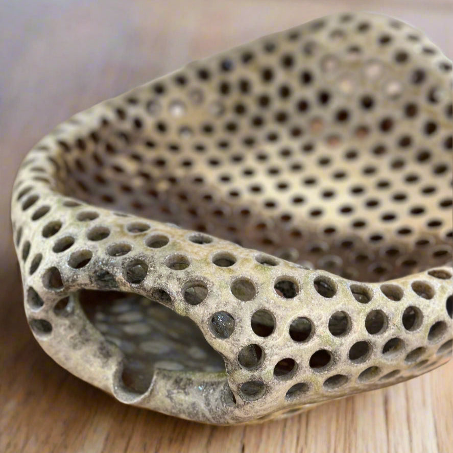 Large ceramic basin serving dish is an open vessel with holes in a white glaze with beautiful warm toned striations by Ian Hazard Bill. Fill it with ice and serve oysters, fill it with fresh picked fruit, fill the bottom with water and place fresh flowers and stems for a dramatic bouquet, or leave it unfilled for a stunning decorative showpiece.