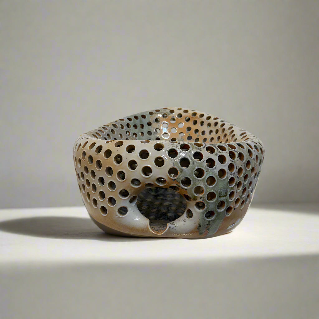 Ceramic bowl with perforated design on a white surface
