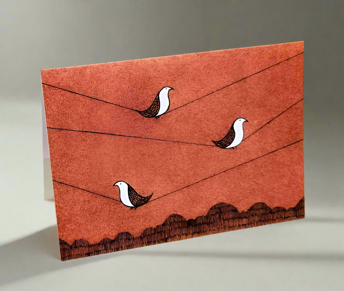 Greeting card with three birds on wire and mountains below.