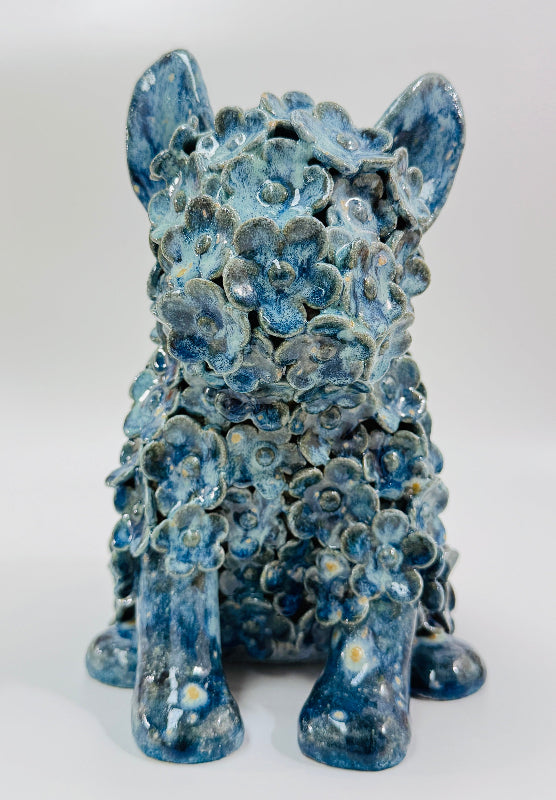A blue glazed ceramic dog sculpture embellished with individually sculpted flowers