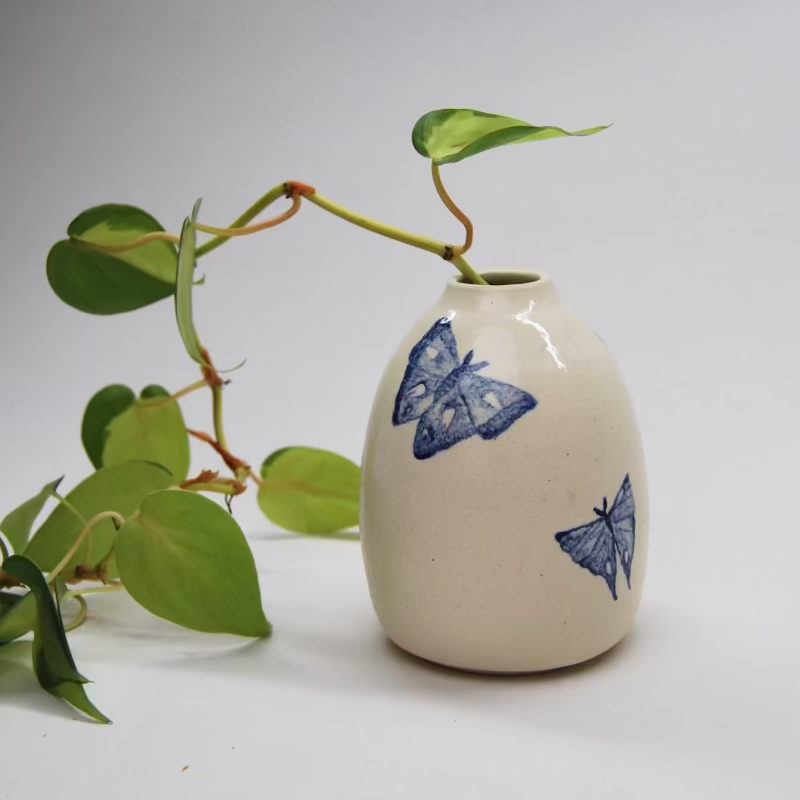 Small white vase with blue watercolor moth designs with green ivy