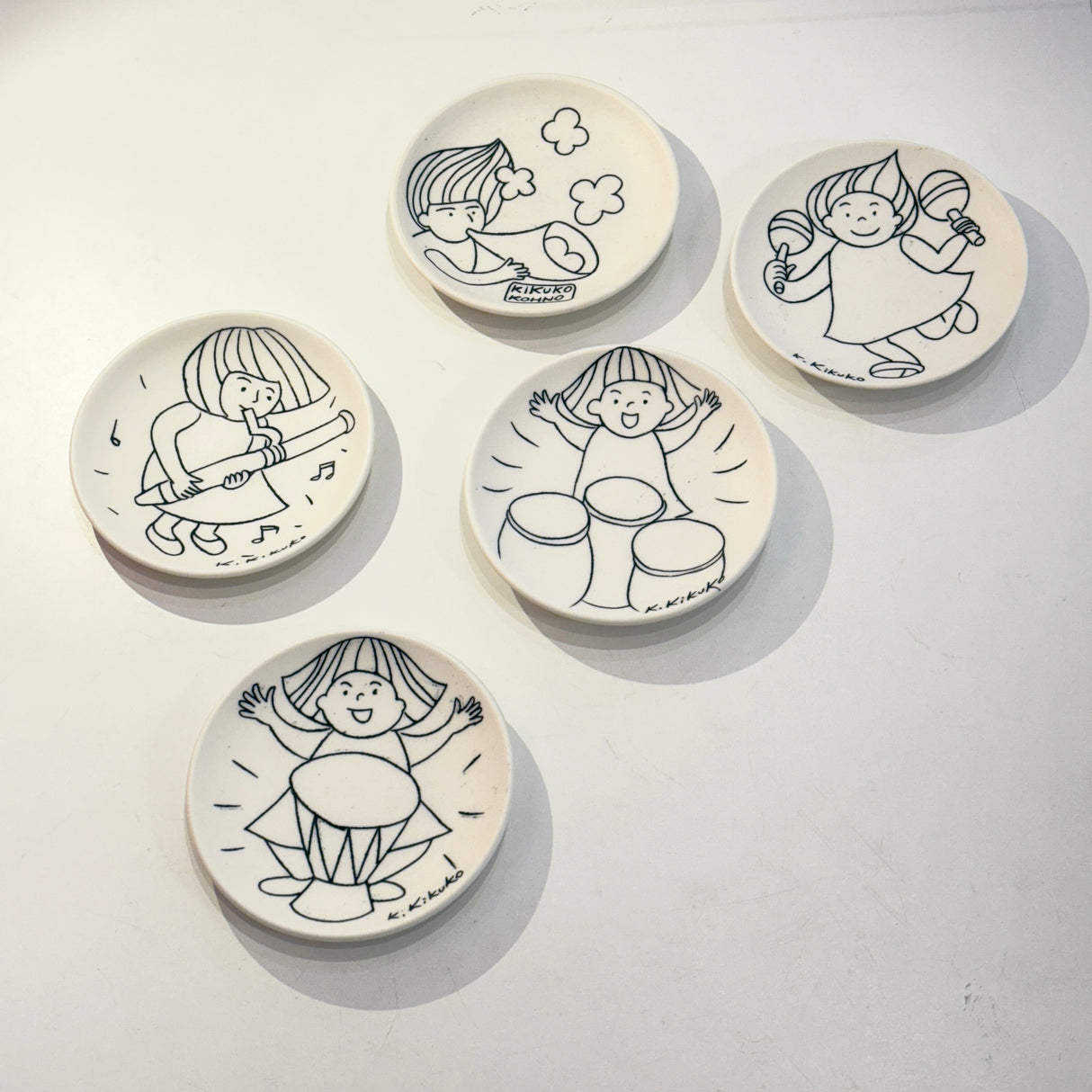 The porcelain plate by Kikuko Kohno is wheel thrown and then decorated in an inlay technique featuring drums and wind instruments.