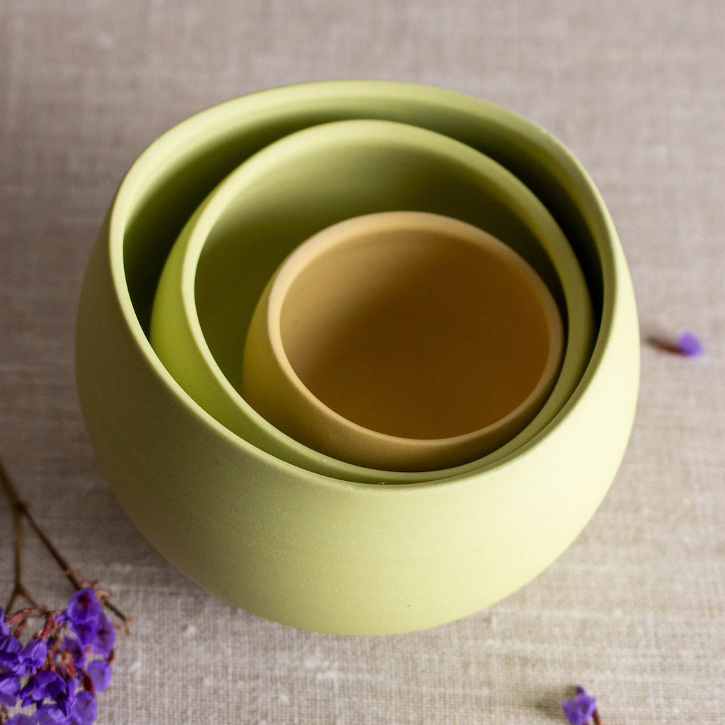 Wheel-thrown porcelain objects by Lisa Fleming. Her pieces are meant to be decorative, and this grouping is her 3 piece wobbles set in lime green and mustard yellow.