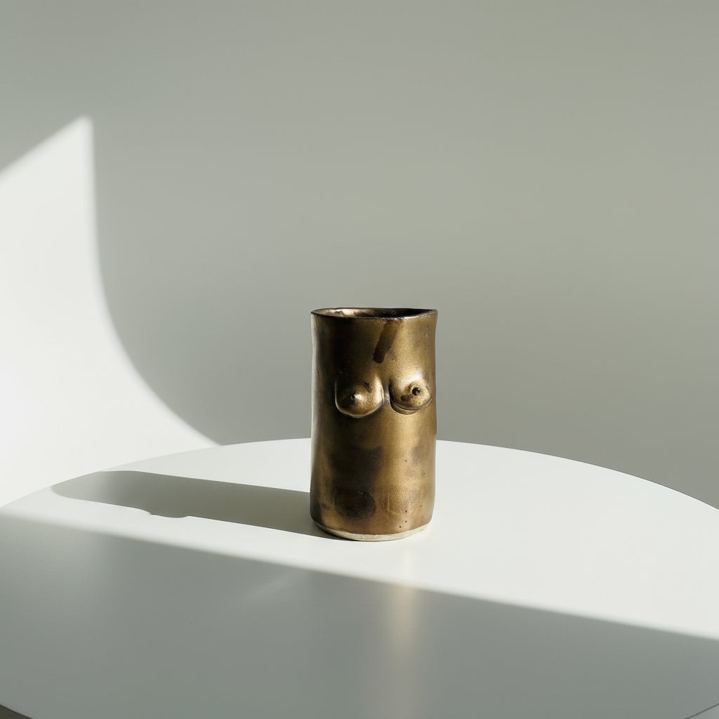 Bronze tittie cup or vase design on a white surface