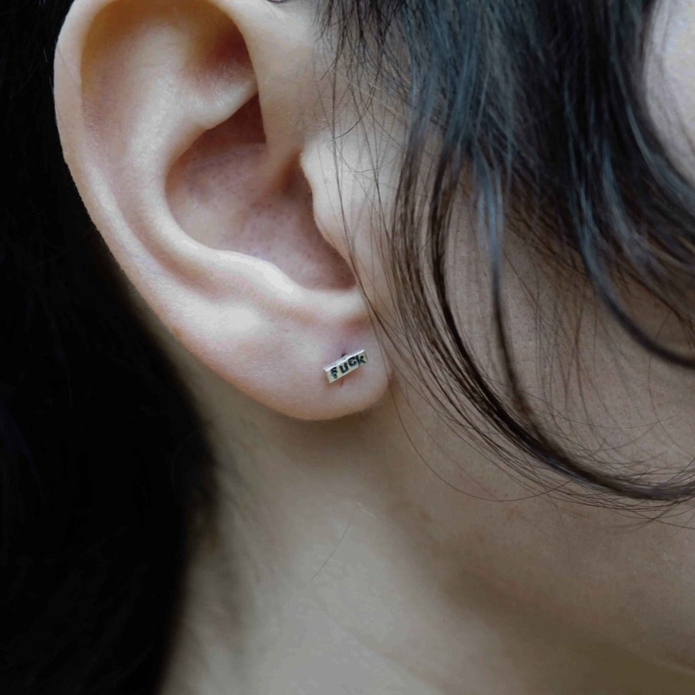 Unleash your inner rebel with these sweet stud earrings, featuring a subtle stamped message. Shown on model.