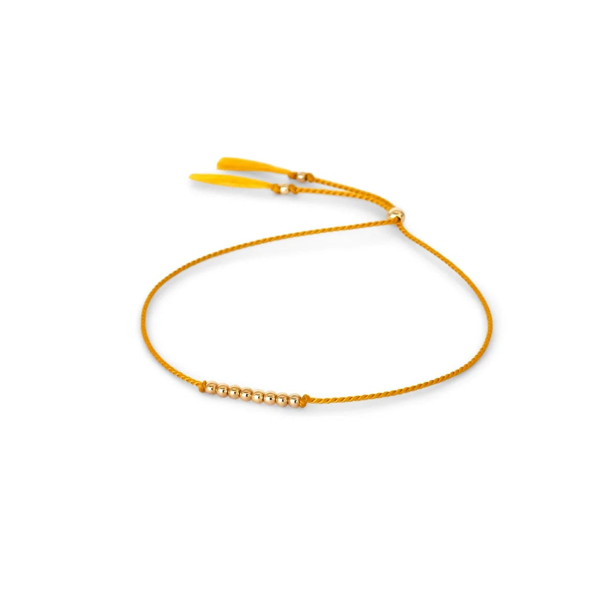 A delicate plantain yellow silk cord bracelet featuring a central cluster of small 14k gold filled beads and adjustable plantain yellow tassel ends, displayed on a clean white background.