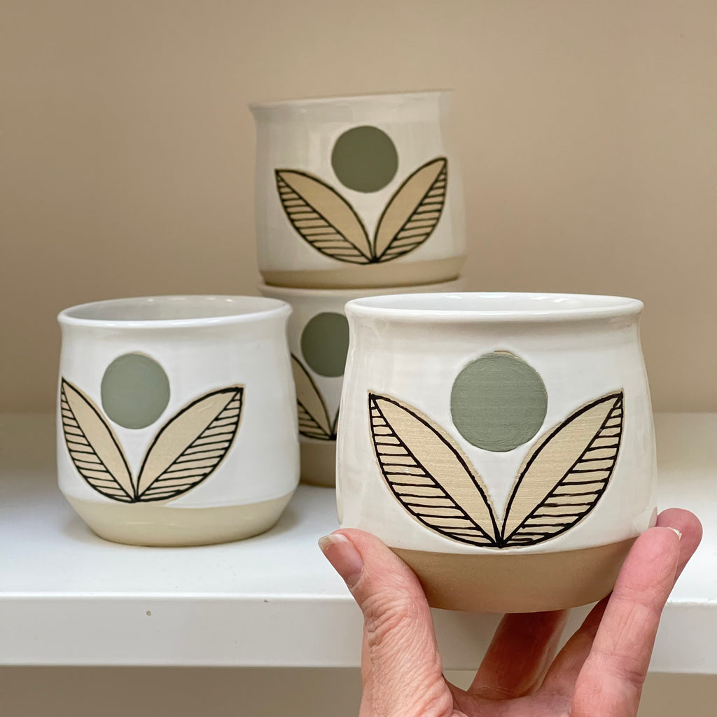 Handle-less mug with a green flower pattern. Judith Lemmens, designer behind the Julems line of wheel thrown ceramics is Dutch and derives inspiration from mid-century and Scandinavian design.