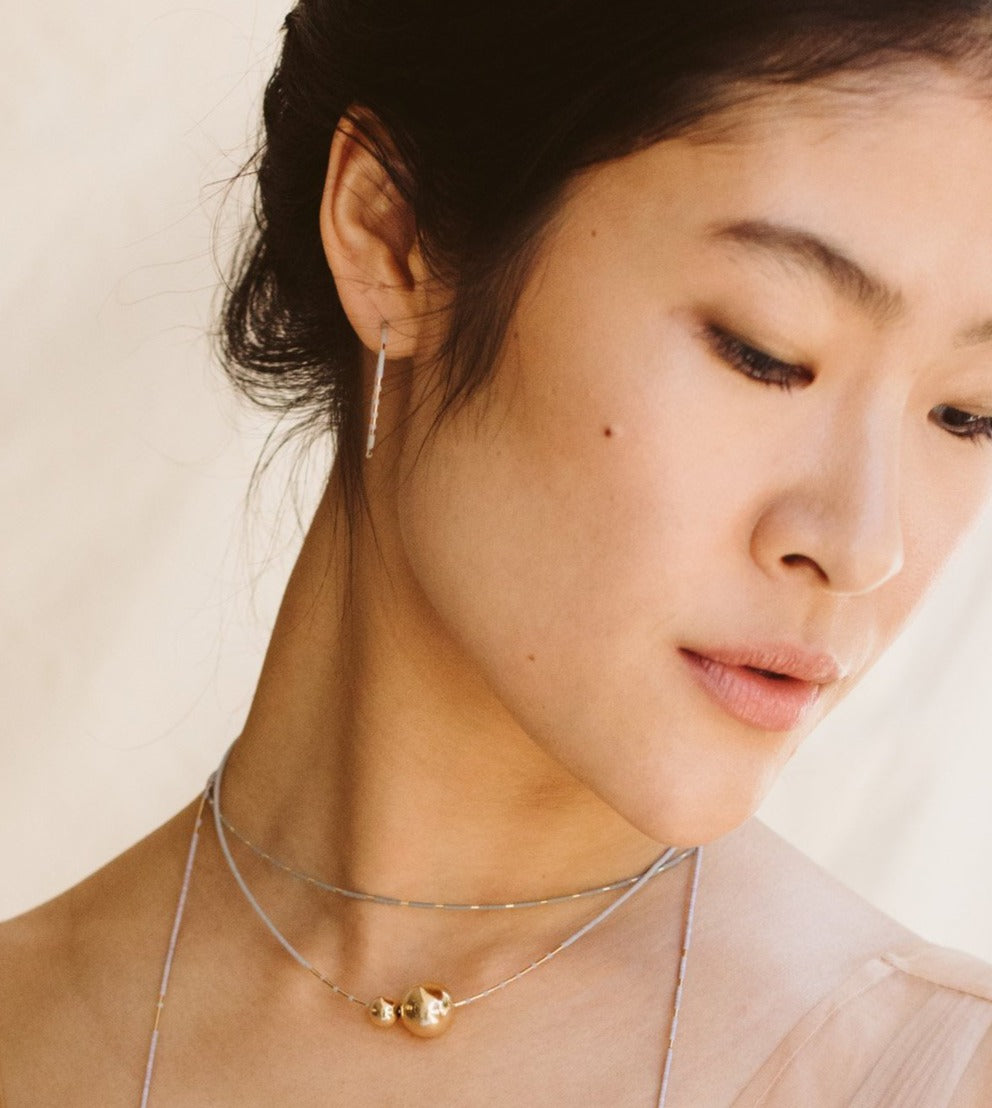 Unexpected patterning of gold among matte glass beads. One earring within each pair features a gold-beaded segment along the backside of the hoop.