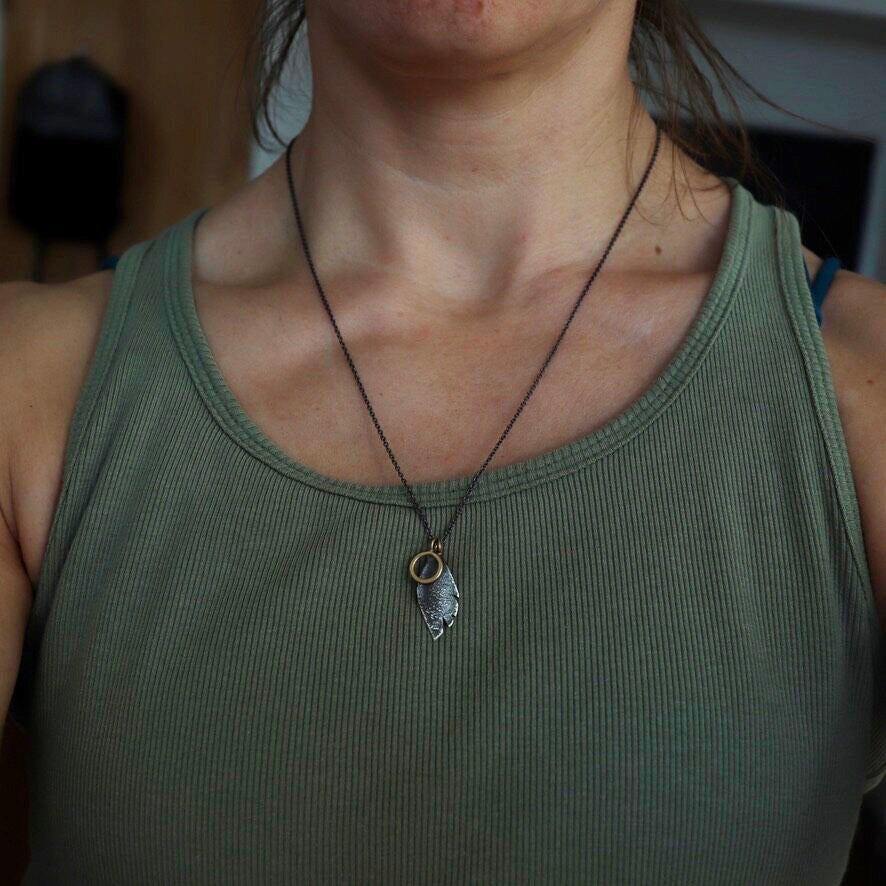 A necklace of tokens, a circle representing the self and a feather of flight and honor, wisdom and freedom.