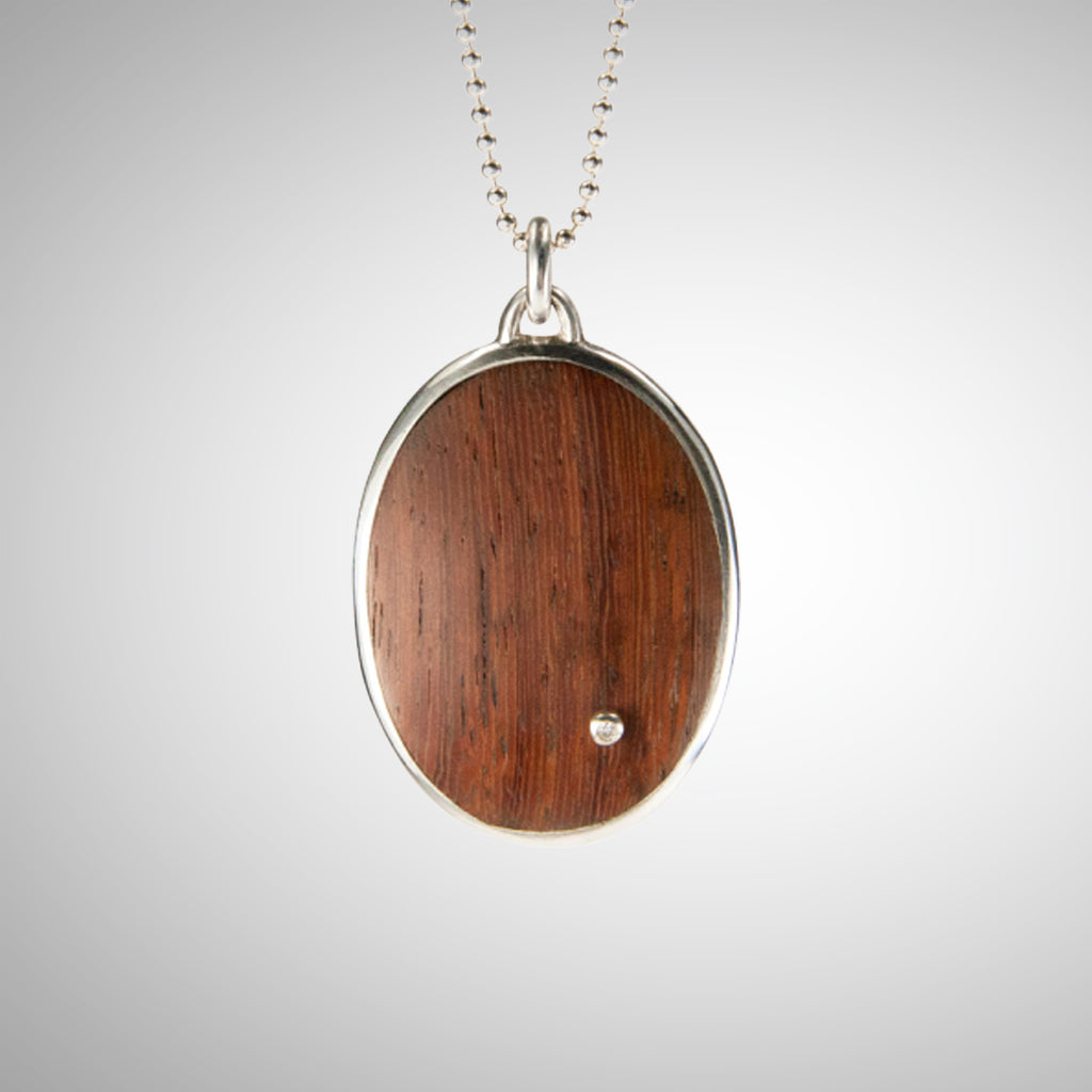 Jeffrey expands his wood collection with a stunning statement necklace using reclaimed wood, gorgeously reused. He cuts the wood to best feature the beauty of the graph lines, from creamy brown to pink-brown. He also makes a setting for a single diamond and pins it through the wood, while setting the two in a large oval sterling setting on chain. 