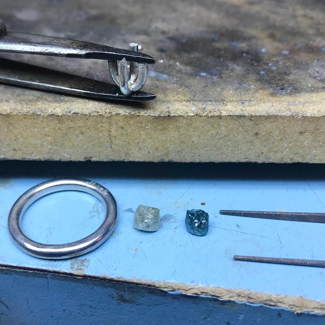 Rough diamond ring settings and rough diamonds in the process of production.