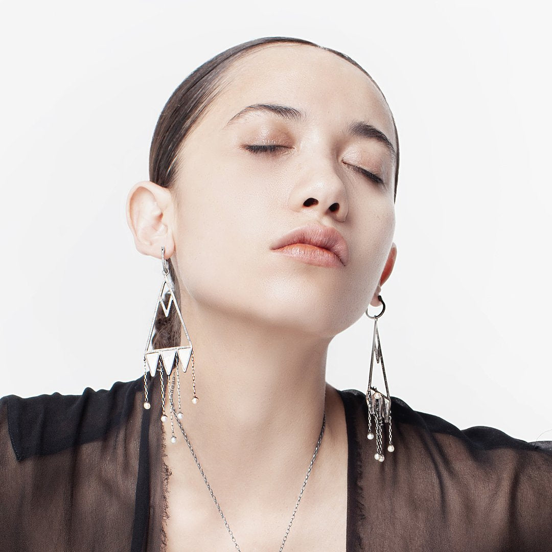These are Mariella's stunning version of chandelier earrings. Rough-hewn rock crystals are cased in etched and oxidized silver to create capture points for hanging pearl raindrops.