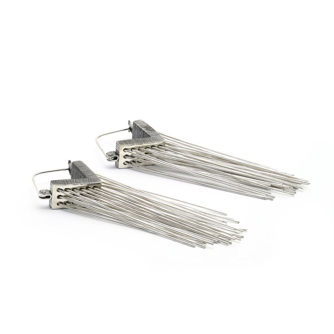 Always stay grounded. These Mariella Pilato earrings feature a cascade of silver wires resting in the air as if the aerial roots of a plant. Side view.