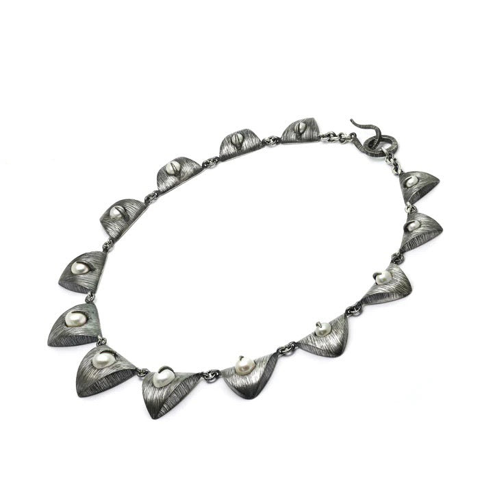 A chain of pearls ensconced in silver triangles descends from largest to smallest in a cascade of pearls and petals. Mariella Pilato designed this crazy cool choker necklace with brilliant detail.