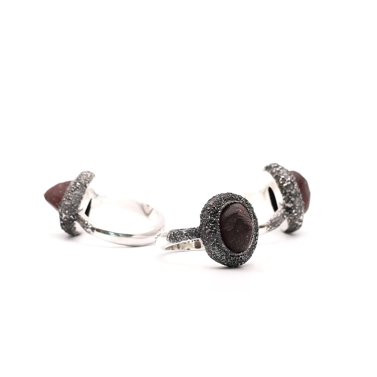 The rough faces of the garnets were found to be intriguing combined with the effect realized by powdering silver and then soldering and oxidizing the it onto the ring itself.