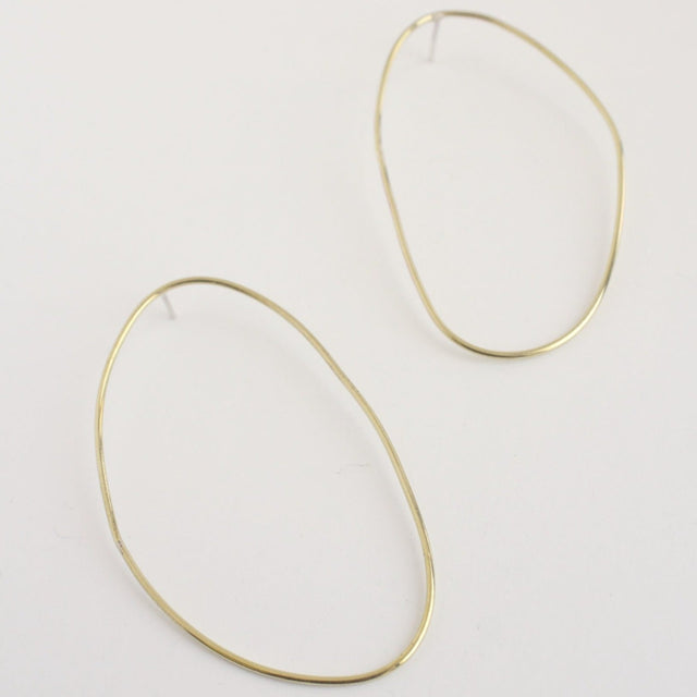 Asymmetrical oval olive-shaped brass earring hoops boast a sophisticated yet modern aesthetic.