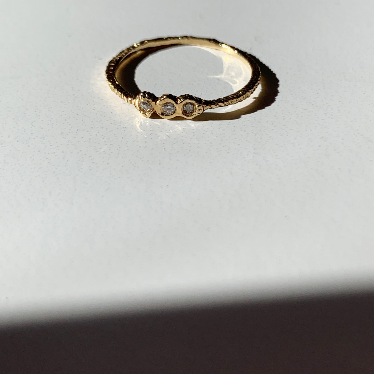 Danielle Welmond adds texture to your ring stack with this elegant yellow gold super skinny etched band set with three white diamonds.