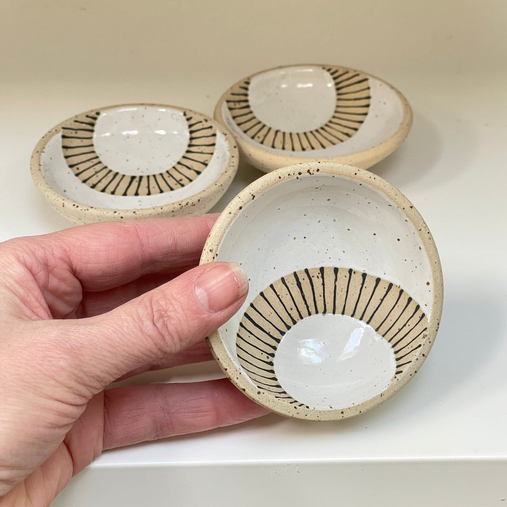 These hand decorated petite dishes are hand thrown on the wheel and features designer Judith Lemmens' Scandinavian-inspired folk art. This pattern is a ‘Radial Cinclement ’ design, using white underglaze on exposed clay.