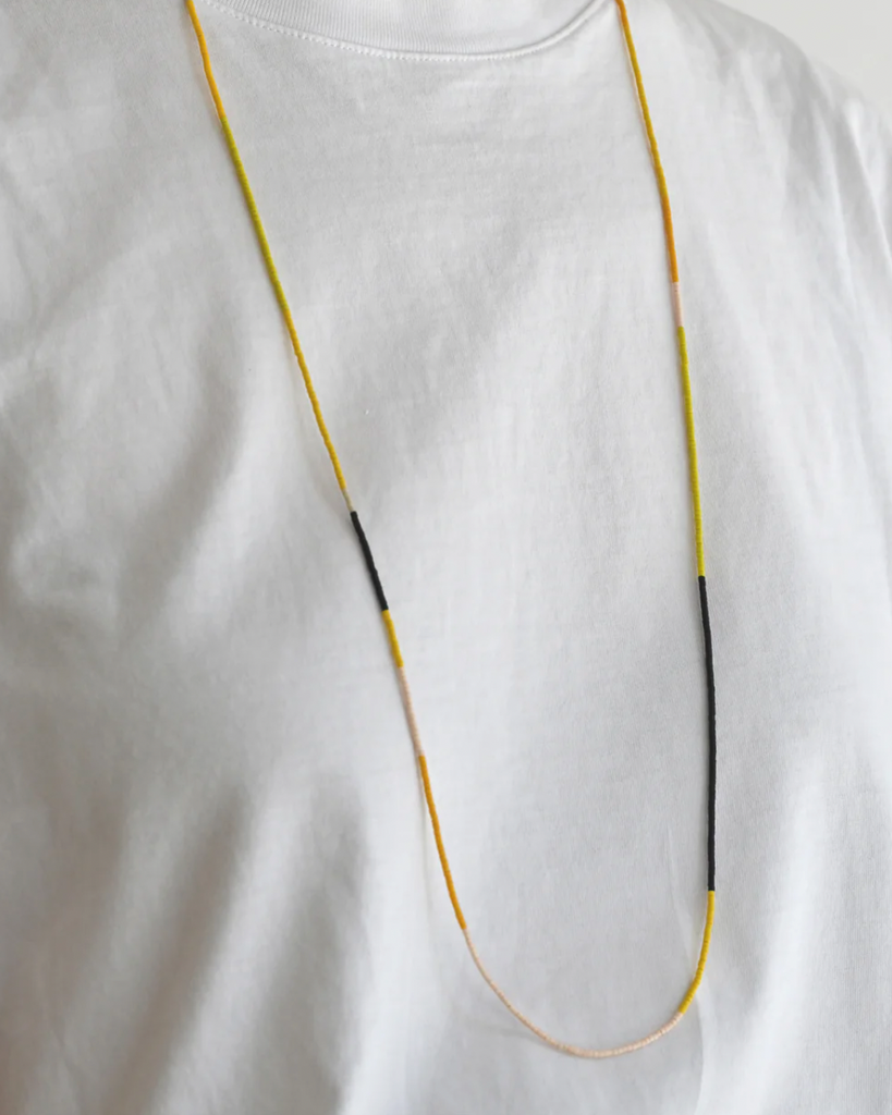 A Yellow Sun long beaded necklace in yellow, pink and black.