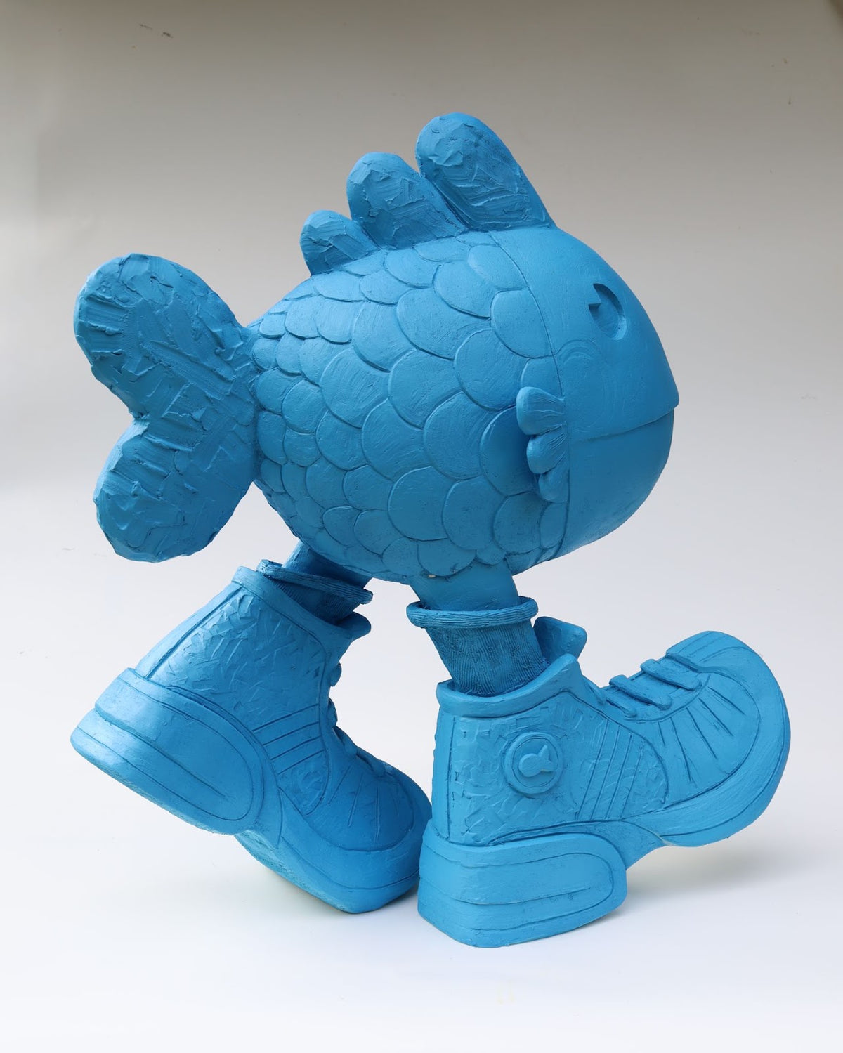 There Is No Such Thing As A Fish is a large, vibrant blue ceramic fish wearing hiking boots, in a walking stance.