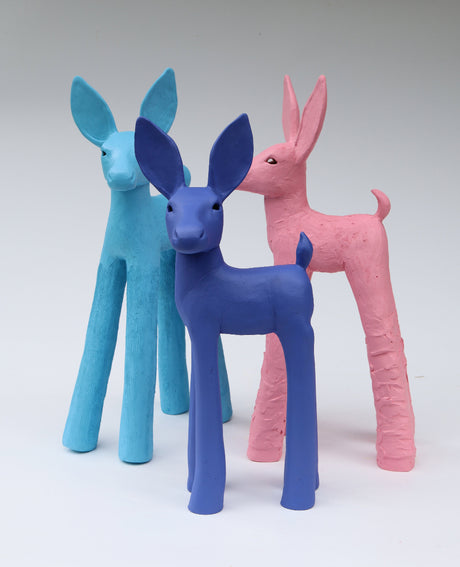 Three colorful deer figurines in blue, purple, and pink on a white background