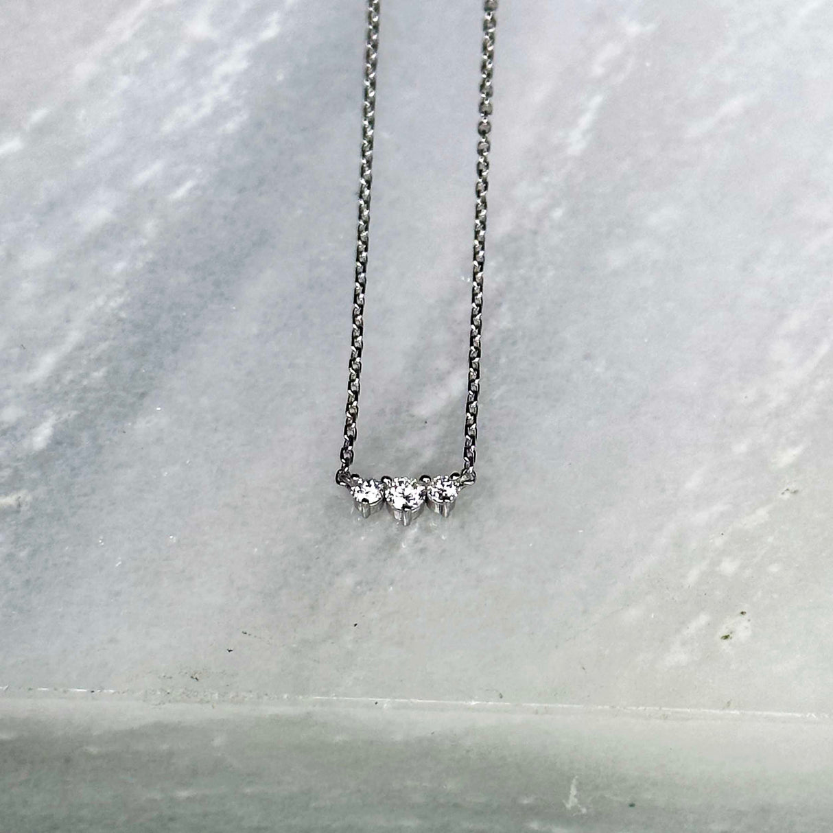 Three diamonds are clustered in a bar in this elegant necklace. 