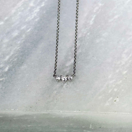 Three diamonds are clustered in a bar in this elegant necklace. 