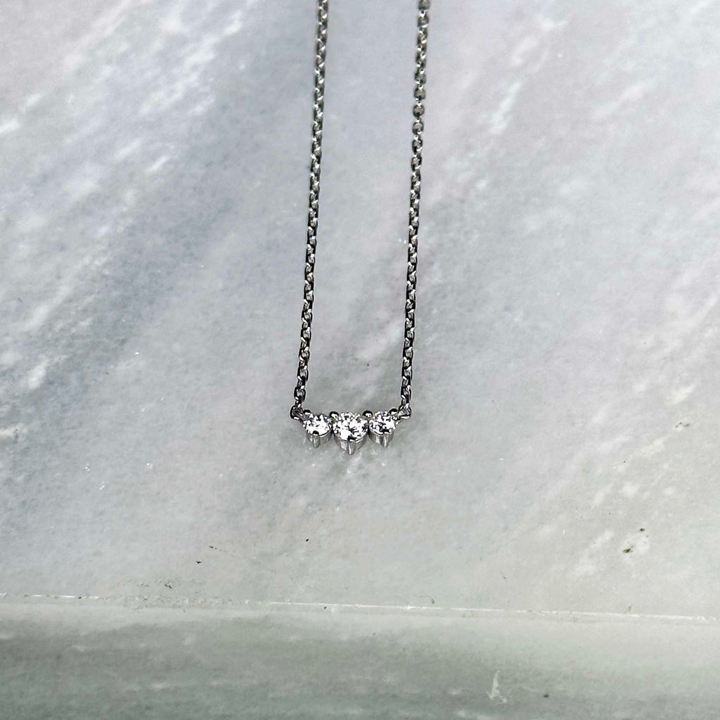 Three diamonds are clustered in a bar in this elegant necklace. 