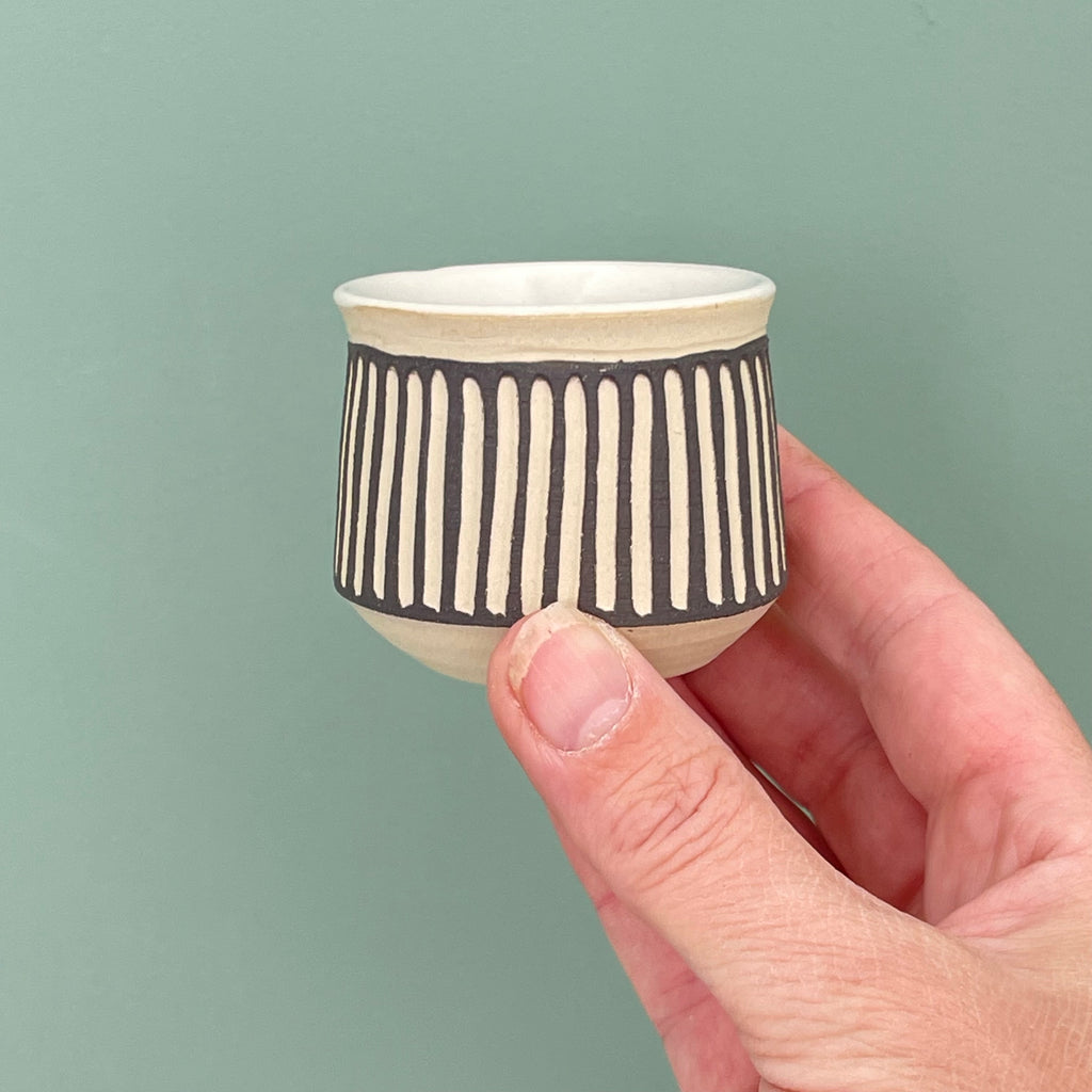 Handmade sake cup or espresso cup, with different decorative techniques. sgraffito technique, where lines are carved through a layer of dark colored slip and left unglazed and dark on the outside