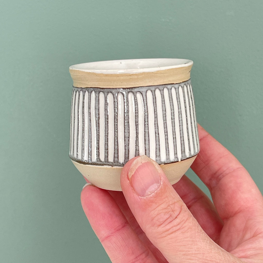Handmade sake cup or espresso cup, with different decorative techniques. Sgraffito technique, where lines are carved through a layer of dark colored slip, finished off with a white glaze for a light profile. 