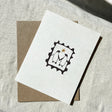 White greeting card with black frame and inside features two penguins and a star