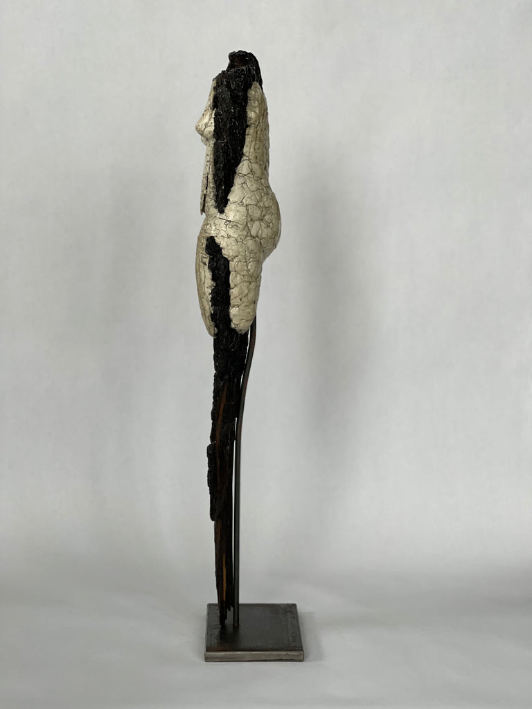 Female figure with sculpted clay around burnt wood and mounted on steel for placement on an entryway table or a dramatic centerpiece for a living room. Side view.