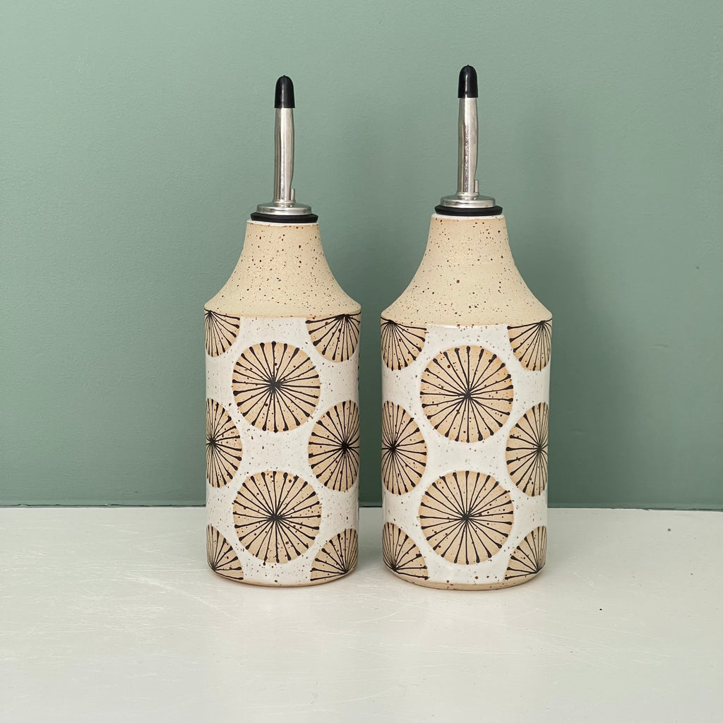 Handmade ceramic oil bottle, made from a light speckled stoneware clay and glazed in white. Hand decorated in a repeating ‘Radial Lines’ pattern using black underglaze on exposed clay. Glazed white on the inside.  