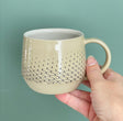 Get cozy with a warm cup, wheel thrown and decorated with a Scandinavian aesthetic. This substantial beauty of a mug comes in 14oz to hold your favorite beverage or soup.  This mug is imprinted with a netting relief, creating a gradient on the body—more defined at the bottom and disappearing higher up. The netting imprint is colored black and glazed in a transparent glaze, while the inside of the mug is glazed in white.