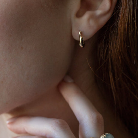 Organic textured and undulating 14K yellow gold huggies to wear everyday–they hug the ear lobe and click into place without backs. Also available in mini. Live, play, sleep in them!&nbsp;