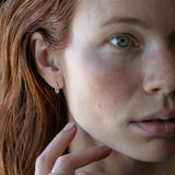 Organic textured and undulating 14K yellow gold mini huggies to wear everyday–they hug the ear lobe and click into place without backs. Also available with charms. Live, play, sleep in them!&nbsp;