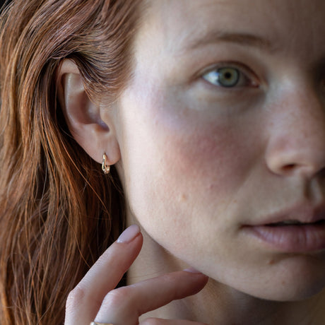 Organic textured and undulating 14K yellow gold mini huggies to wear everyday–they hug the ear lobe and click into place without backs. Also available with charms. Live, play, sleep in them!&nbsp;