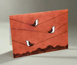 Greeting card with three birds on wire and mountains below. 