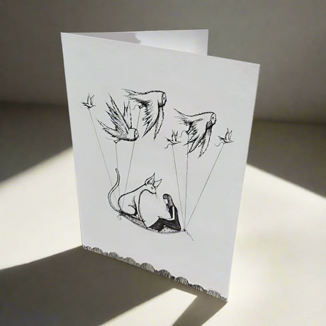 Greeting card with pencil and pen drawing of a cat and girl on a magic carpet, carried by birds through the sky