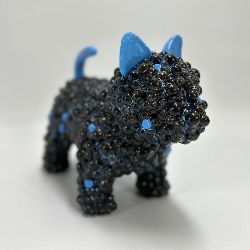 This is Midnight Companion, a tail wagging ceramic dog sculpture in deep blue glaze with contrasting bright blue ears and tail.