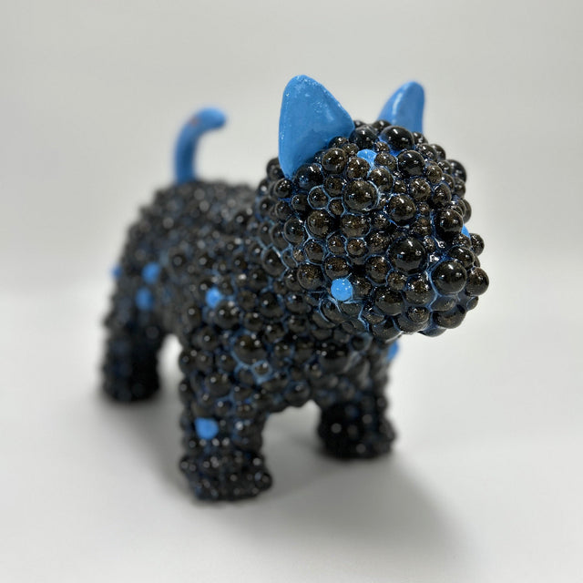 This is Midnight Companion, a tail wagging ceramic dog sculpture in deep blue glaze with contrasting bright blue ears and tail.