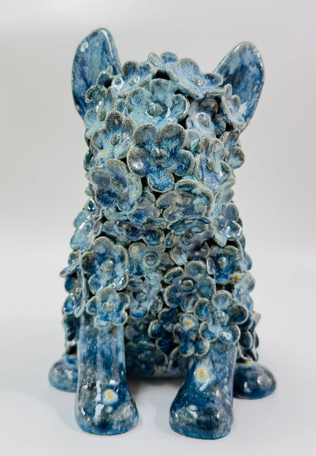 A blue glazed ceramic dog sculpture embellished with individually sculpted flowers 