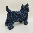 A ceramic dog sculpture made of tightly clustered dark blue rounded gum ball adornments, in a deep blue glaze