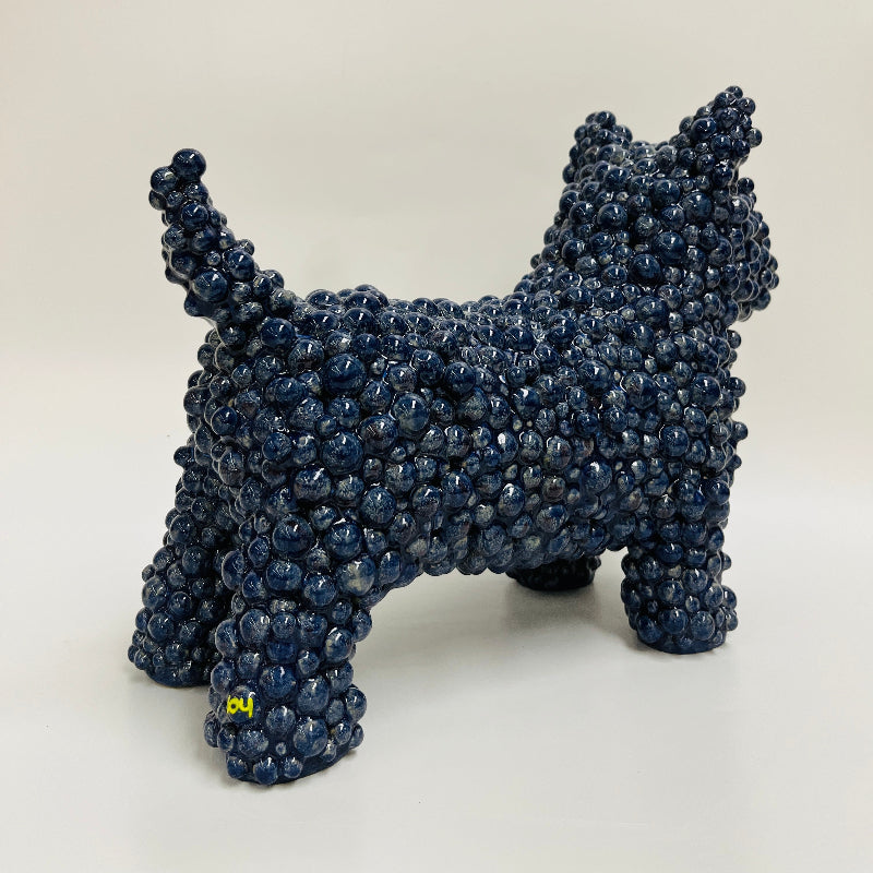 A ceramic dog sculpture made of tightly clustered dark blue rounded gum ball adornments, in a deep blue glaze