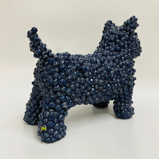 A ceramic dog sculpture made of tightly clustered dark blue rounded gum ball adornments, in a deep blue glaze