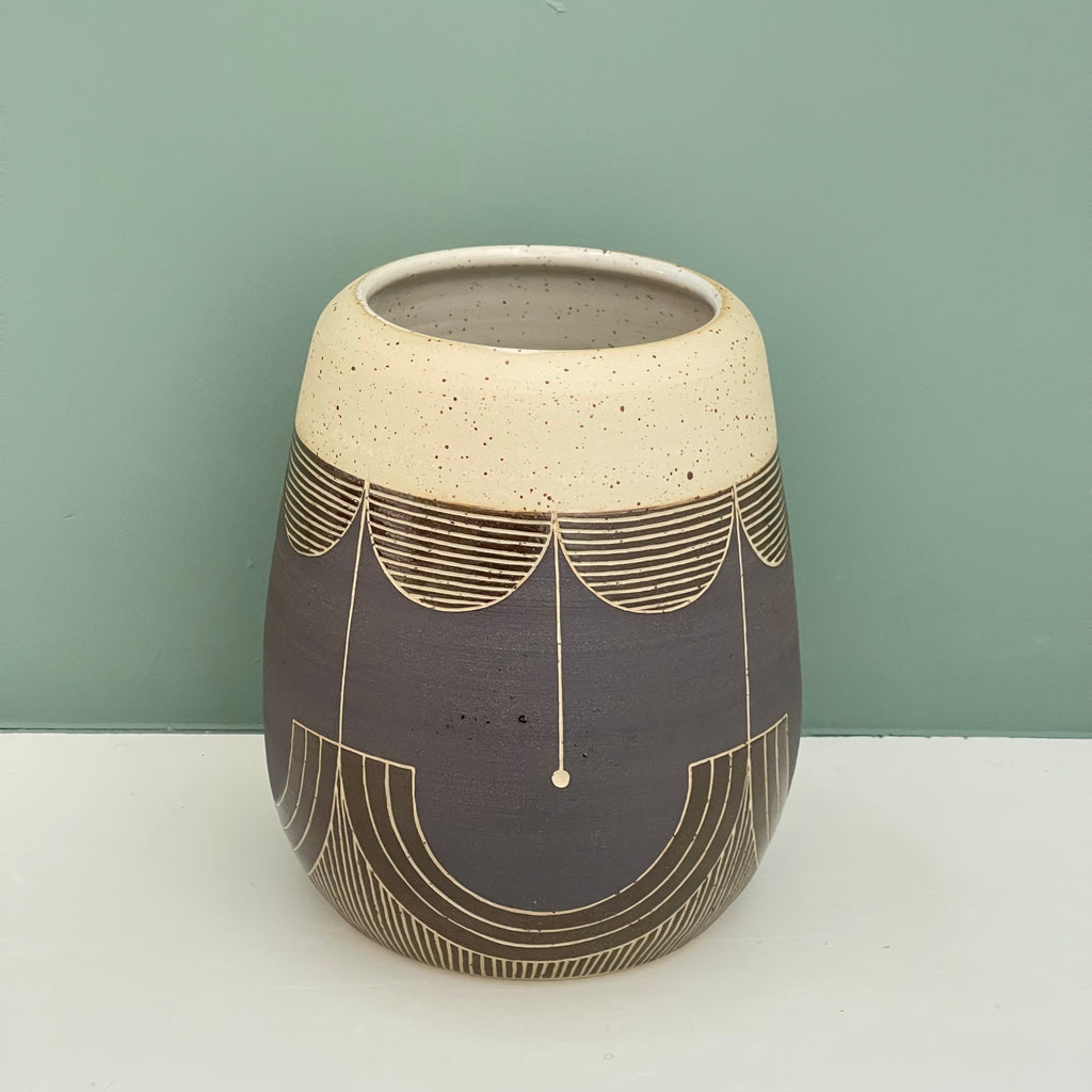 Growing up in the Netherlands, Judith was surrounded by design influences. She has a strong Mid Century Modern vibe with simple shapes and designs that accentuate that shape, often using a calculated repetitive pattern. This gorgeous wheel thrown vase is a delicious rich glaze with a hand carved geometric design and fresh style.